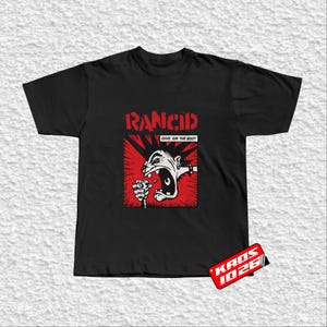 Puede incluir: Camiseta negra con un gráfico rojo y blanco de una figura gritando. La palabra "Rancid" está encima del gráfico y "Give Em The Boot" debajo. El diseño está sobre un fondo rojo.