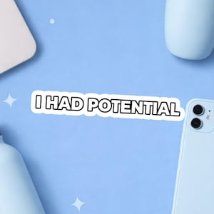 May include: A white sticker with black border and the text "I HAD POTENTIAL" on a light blue surface. A light blue phone, a white laptop, and other light blue objects are also visible.