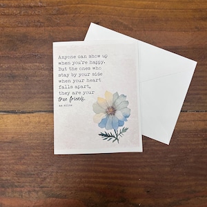 May include: Greeting card with a floral design and the quote "Anyone can show up when you're happy. But the ones who stay by your side when your heart falls apart, they are your true friends." Includes a white envelope.