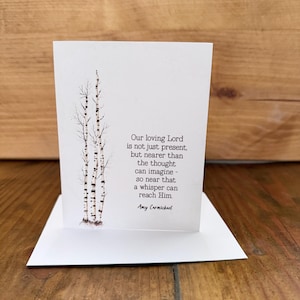 May include: A white greeting card with a watercolor illustration of birch trees. The card features the quote, "Our loving Lord is not just present, but nearer than the thought can imagine - so near that a whisper can reach Him." by Amy Carmichael.