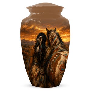 May include: A cylindrical cremation urn with a smooth, rounded lid, featuring a printed scene of a person with long dark hair standing beside a horse in a landscape at sunset. The horse displays painted markings, including a handprint on its flank.