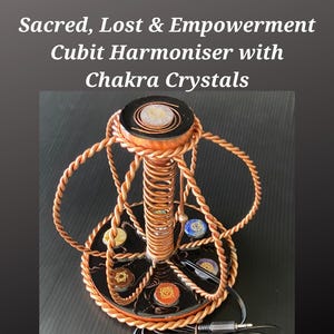 May include: A copper-toned Cubit Harmoniser with Chakra Crystals. The device features a central coil, decorative rope-like wiring, and a base adorned with colorful chakra symbols. The text "Sacred, Lost & Empowerment Cubit Harmoniser with Chakra Crystals" is displayed.