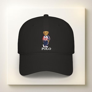 Könnte beinhalten: Schwarze Baseballkappe mit einem Cartoon-Bären, der ein Outfit im Union-Jack-Stil trägt und einen Poloschläger hält. Das Wort "POLO" ist darunter in Weiß gedruckt.