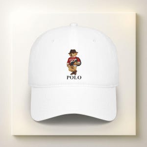 May include: White baseball cap featuring a Polo bear wearing a red and black sweater and a brown hat. The word "POLO" is printed in black below the bear illustration. A classic, casual accessory.