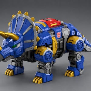 May include: A blue, yellow, and gray robotic Triceratops toy with gold horns and accents. The toy has a red panel on its back and the Transformers logo. The toy is a detailed, articulated figure.
