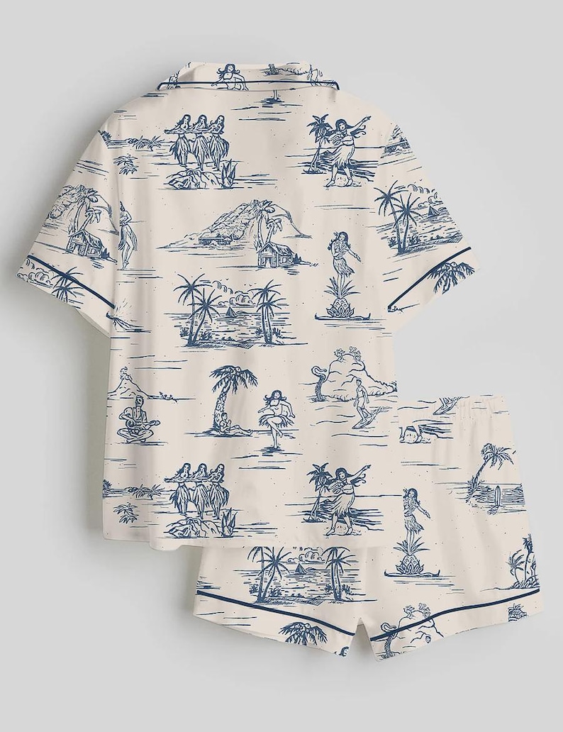 May include: A two-piece pajama set featuring a cream-colored background with a blue island-themed print. The set includes a short-sleeved button-up shirt and matching shorts, both trimmed with a dark blue border. The print depicts palm trees, dancers, and musicians.