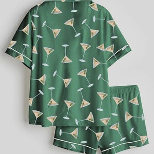 K&ouml;nnte beinhalten: Gr&uuml;nes Pyjama-Set mit einem Muster aus Martinigl&auml;sern. Das kurz&auml;rmelige Oberteil und die Shorts haben wei&szlig;e Paspeln. Die Martinigl&auml;ser sind beige mit gr&uuml;nen Oliven.