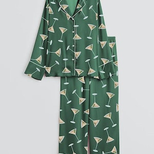 K&ouml;nnte beinhalten: Gr&uuml;nes Pyjama-Set mit Martini-Glas-Muster. Das lang&auml;rmlige Oberteil hat eine Knopfleiste und wei&szlig;e Paspeln. Die passende Hose ist gerade geschnitten. Der Pyjama ist aus seidigem Material.