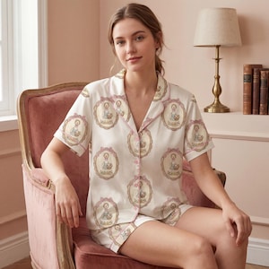 Może przedstawiać: Kremowy zestaw piżamowy z powtarzającym się owalnym wzorem z postacią trzymającą kosz. Kr&oacute;tki rękaw top i szorty mają r&oacute;żowe wykończenia i guziki. Zestaw wykonany jest z miękkiej, lekkiej tkaniny.