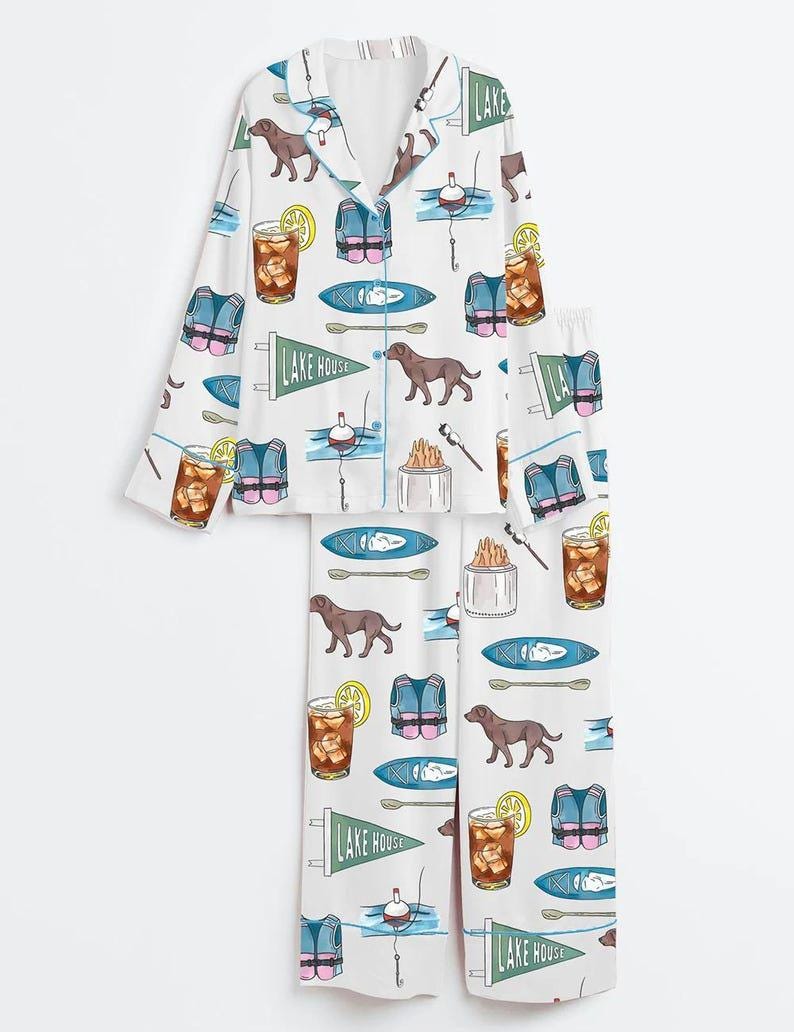 Peut inclure: Ensemble de pyjama blanc avec un motif r&eacute;p&eacute;t&eacute; d'illustrations sur le th&egrave;me du lac. Le motif comprend des chiens bruns, des gilets de sauvetage, des kayaks, des flotteurs de p&ecirc;che et des cocktails au citron. L'ensemble comprend une chemise boutonn&eacute;e &agrave; col et un pantalon assorti.