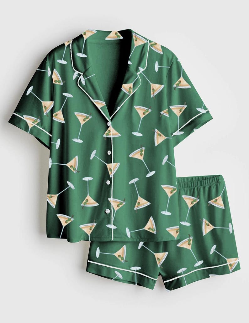 K&ouml;nnte beinhalten: Gr&uuml;nes Pyjama-Set mit Martini-Muster. Das kurz&auml;rmelige Oberteil und die Shorts sind mit wei&szlig;en Zierleisten und einem sich wiederholenden Design von Martinigl&auml;sern mit Oliven versehen. Das Set ist aus einem weichen, leichten Stoff gefertigt.