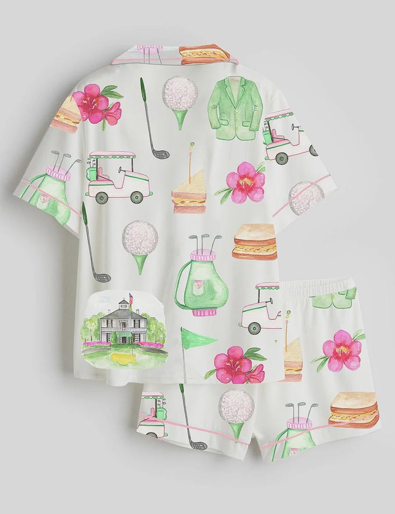 May include: White pajama set with a golf-themed watercolor print. The set includes a short-sleeved button-up shirt and shorts. The print features golf balls, golf carts, sandwiches, pink flowers, golf clubs, and a green blazer.