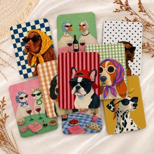 Op de afbeelding: Een verzameling rechthoekige kaarten met illustraties van honden en katten die hoofddoeken en zonnebrillen dragen. De ontwerpen bevatten diverse patronen zoals ruiten, strepen en stippen, waarbij sommige kaarten dieren aan tafels met wijn tonen.