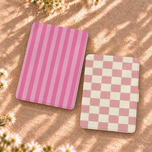 May include: Two rectangular e-reader cases. The larger case features a vertical striped pattern in two shades of pink. The smaller case displays a checkered pattern consisting of alternating light pink and off-white squares.