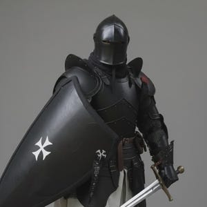Puede incluir: Una armadura de caballero negra completa, que incluye un casco, peto y protecci&oacute;n para las piernas. El escudo es negro con una cruz blanca. Una espada se sostiene en la mano derecha. La armadura se usa sobre una t&uacute;nica blanca.