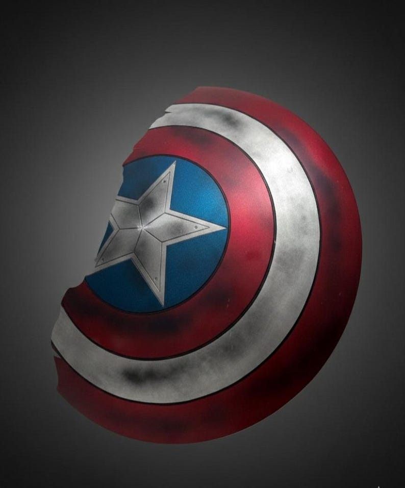 May include: A Captain America shield, featuring a red, white, and blue color scheme. The shield has a central blue circle with a white star, surrounded by red and white concentric rings. The shield has a distressed, battle-worn appearance.
