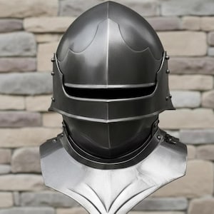 May include: A metallic silver knight's helmet with a visor and neck guard. The helmet has a rounded top and is riveted along the sides. The neck guard is shaped with a pointed bottom. The background is a brick wall.