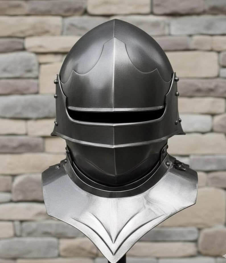 May include: A metallic silver knight's helmet with a visor and neck guard. The helmet has a rounded top and is riveted along the sides. The neck guard is shaped with a pointed bottom. The background is a brick wall.