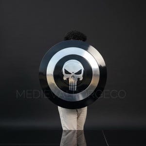 May include: A large, round shield with a black and silver design. The shield features a skull emblem in the center. The text "MEDIEVALFORGECO" is printed on the shield.