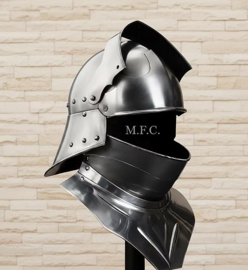 May include: A polished, silver-colored medieval helmet with a visor and neck guard. The helmet has rivets and a curved top, with the text "M.F.C." visible on the front. The design suggests historical armor.