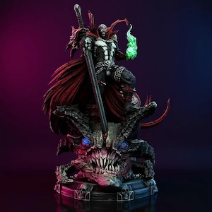 May include: A detailed statue of the comic book character Spawn. The figure is clad in a black and white suit with a red cape, holding a large sword and a green flame. The statue is mounted on a detailed base with skulls and a demonic face.