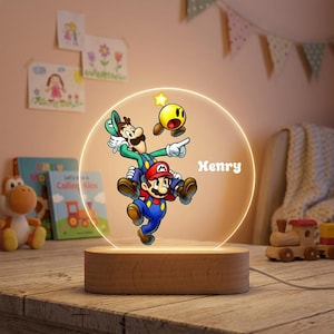 May include: A circular acrylic night light with a wooden base featuring a colorful graphic of Mario carrying Luigi and a yellow star. The name Henry is printed in white text on the right side of the illuminated circular display panel.