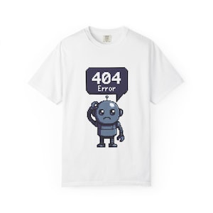 Könnte beinhalten: Weißes T-Shirt mit einem pixeligen Roboter und einer Sprechblase mit der Aufschrift "404 Error". Der graue Roboter scheint betrübt zu sein. Das T-Shirt hat einen Rundhalsausschnitt.