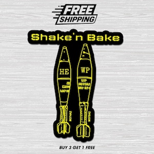 May include: Black sticker with yellow outline featuring two stylized bomb illustrations labeled "HE" and "WP". The text "Shake'n Bake" is above the bombs, and "FREE SHIPPING" is at the top. The bottom reads "BUY 3 GET 1 FREE".