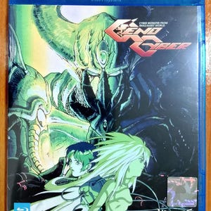 Puede incluir: Una caja de disco Blu-ray azul con el anime "Genocyber". La portada muestra un monstruo verde y negro, dos personajes de anime y el título "END CYBER" en rojo. La caja también incluye el texto "VAMPIRE HOUSE."