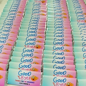 May include: A large collection of rectangular chocolate bars wrapped in a gradient paper featuring a blue to pink transition. Each wrapper displays the text Good Bye! in blue, a waving emoji, and the text Thanks for the memories Love Simone X.