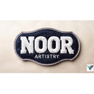 Op de afbeelding: Een marineblauwe stoffen patch met een geschulpte rand en een lichtgrijze boord. De patch bevat het woord NOOR in grote, witte, getextureerde, verhoogde letters, met het woord ARTISTRY in kleinere, witte, platte letters eronder.