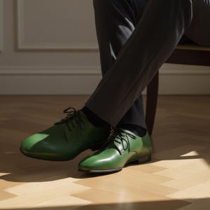 May include: A pair of green leather dress shoes with black laces. The shoes are worn with dark gray trousers and black socks. The shoes have a classic, polished appearance.