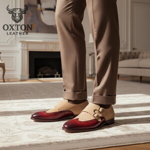 May include: Burgundy and tan leather dress shoes with a double buckle design. The shoes are worn with brown trousers. The Oxton Leather logo is visible in the background. The shoes are a stylish footwear choice.