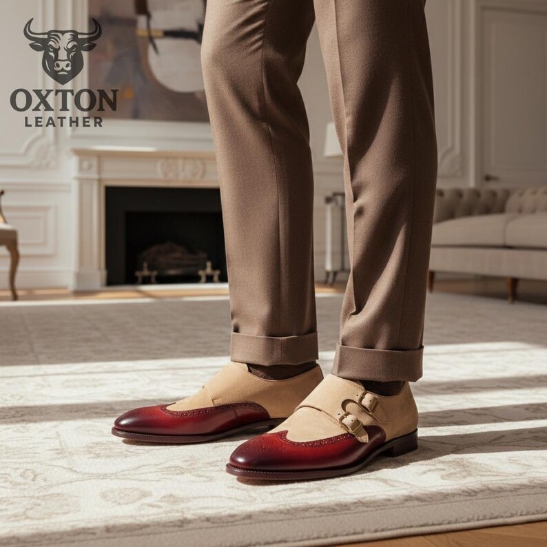 May include: Burgundy and tan leather dress shoes with a double buckle design. The shoes are worn with brown trousers. The Oxton Leather logo is visible in the background. The shoes are a stylish footwear choice.