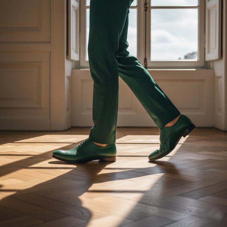 May include: Green leather dress shoes with a classic lace-up design. The shoes are paired with matching green trousers. The image is taken indoors with natural light, highlighting the texture and color of the shoes.