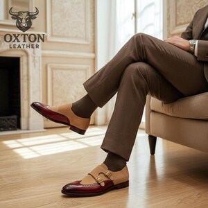 May include: Two-tone leather dress shoes with a double monk strap buckle closure. The shoes feature a burgundy toe and heel, tan suede midsection, and a brown sole. The Oxton Leather logo is visible in the upper left corner.