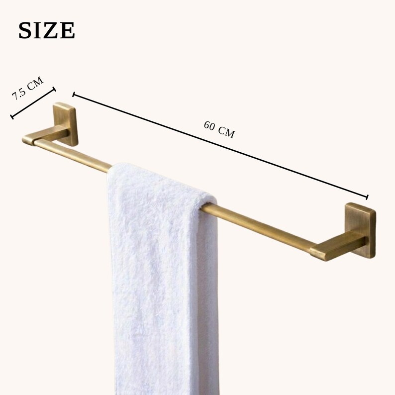 Peut inclure: Un porte-serviettes de couleur laiton avec une serviette blanche suspendue. La barre mesure 60 cm de long et 7,5 cm de large. Le mot "SIZE" est visible en haut &agrave; gauche.