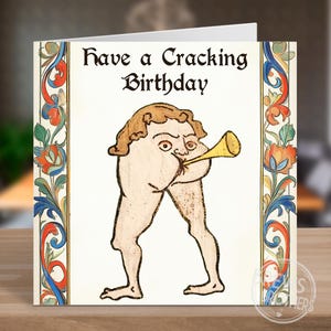Puede incluir: Tarjeta de felicitaci&oacute;n de cumplea&ntilde;os con una ilustraci&oacute;n medieval de una figura tocando una trompeta. La tarjeta presenta el texto "Have a Cracking Birthday" en una fuente decorativa, con un borde floral colorido.