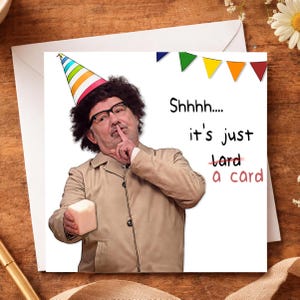 May include: A funny birthday card with a man in a party hat, holding a gift, and shushing. The card says "Shhhh.... it's just a card.", with a crossed-out word.