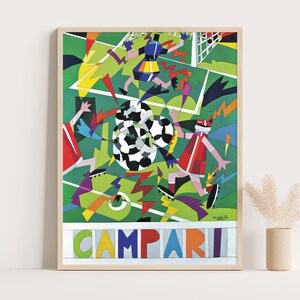 May include: A framed poster featuring a stylized, geometric illustration of a soccer match on a green field. Players in red and blue uniforms compete for a black and white soccer ball. The word CAMPARI is printed in large, colorful letters at the bottom.
