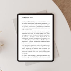 May include: A black tablet displaying text titled "Strong Example Answer". The text describes a new customer preference feature, data models, and testing processes. The tablet is on a white surface.