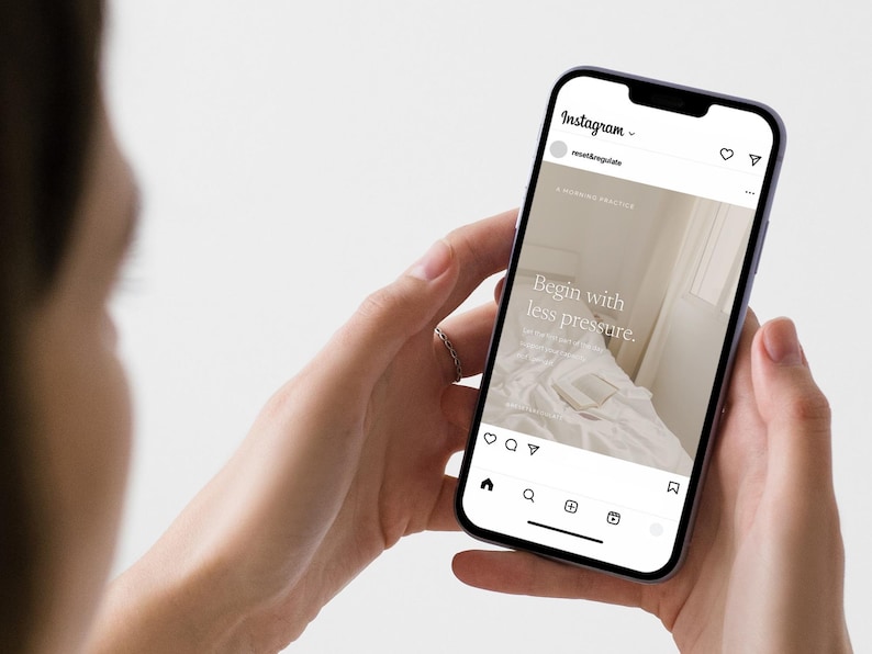 A visual of person holding a phone in two hands displaying an Instagram post that reads "Begin with less pressure" over a soft bedroom photograph, showing how the template appears on a real Instagram feed.