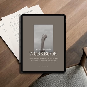 Op de afbeelding: Een digitale tablet met een taupekleurige omslag voor een Wellness Coach werkboek, met een zwart-witfoto van opgeheven handen, en de tekst "WELLNESS COACH WORKBOOK" en "CLIENT FACING WORKSHEETS FOR INTAKE, SESSIONS, TRACKING & REFLECTION".