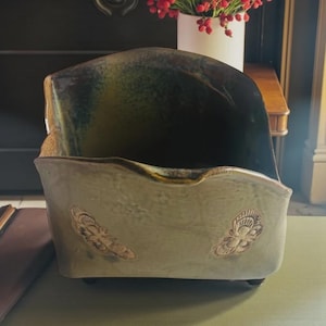 Peut inclure: Un porte-lettres en céramique, vert et marron, avec des motifs de papillons en relief. L'intérieur est brillant et le porte-lettres repose sur de petits pieds. Un objet décoratif pour la maison ou le bureau.