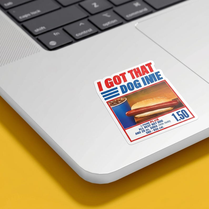 May include: A sticker with the text "I GOT THAT DOG IN ME" in red and blue. The sticker features an image of a hot dog and soda. The text "1/4 POUND PLUS ALL BEEF HOT DOG AND 20 oz. SODA" is also included.