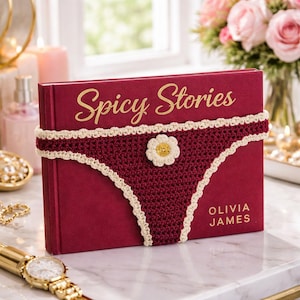 May include: A burgundy book titled "Spicy Stories" with gold lettering, adorned with a crocheted underwear design in burgundy and cream. A cream daisy embellishes the center. The author's name, Olivia James, is printed at the bottom.