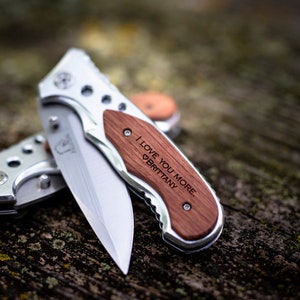 May include: A silver pocket knife with a wooden handle engraved with the words "I love you more, Brittany".