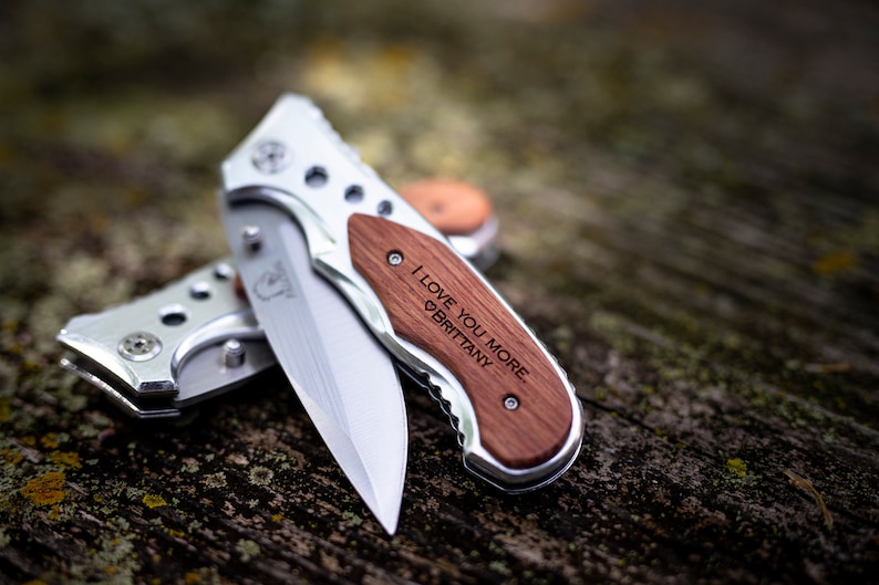 May include: A silver pocket knife with a wooden handle engraved with the words "I love you more, Brittany".