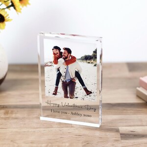 May include: A clear acrylic photo block with a picture of a couple on a beach. The text "Happy Valentine's Day I love you - Ashley xoxo" is printed on the block.