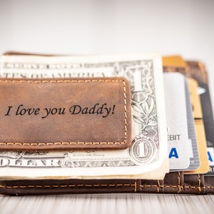 May include: A brown leather wallet with a money clip. The wallet has the words "I love you Daddy!" engraved on the front.